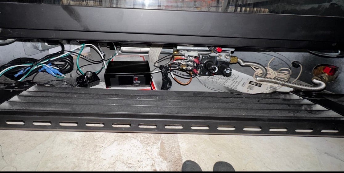 Fireplace lower compartment with wiring and control components visible