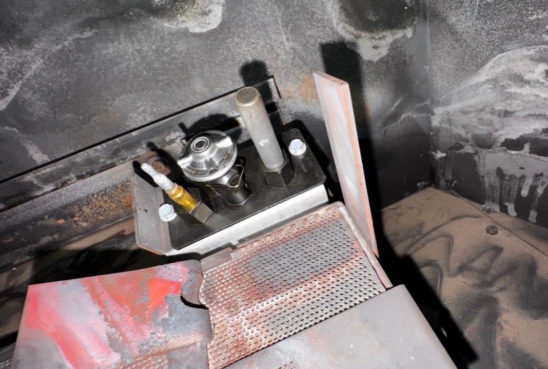 Close-up of pilot assembly beside a gas fireplace burner