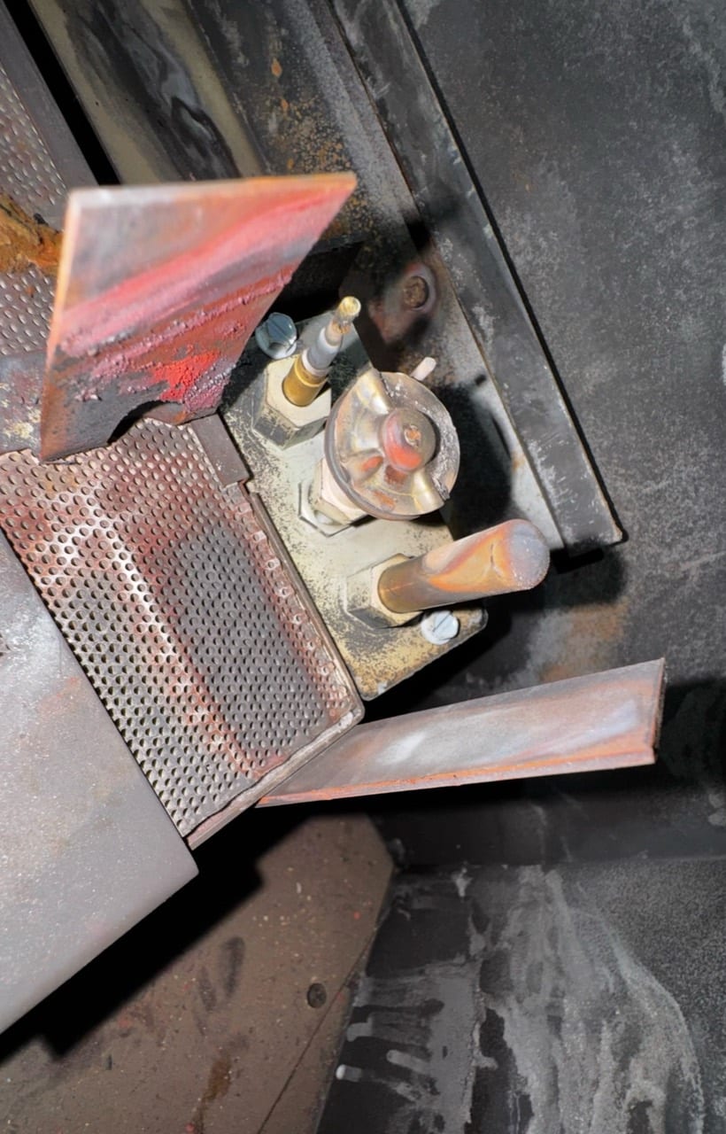 Overhead detail of a fireplace pilot and adjacent metal burner