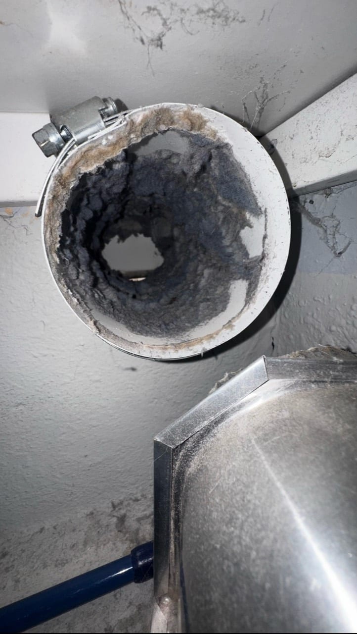 Round metal vent connection showing accumulated lint and dust