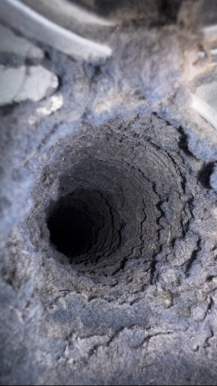 Interior of a vent with dense lint buildup along its walls